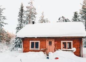 Snow covered Chalet Experience the serene beauty of a snow-covered wooden cabin amidst the Finnish woods during winter.